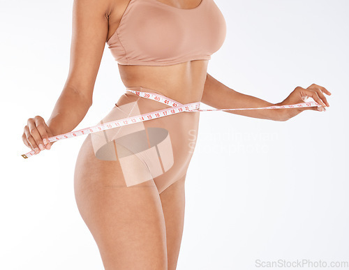 Image of Tape, fitness and woman body isolated on a white background for lose weight or tummy tuck in underwear. Model person in lingerie, measure waist or stomach for liposuction results or health in studio