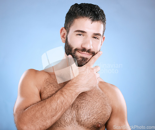 Image of Skincare, beauty and portrait of man with beard, hand on face and cleaning treatment isolated on blue background. Facial hygiene, happy male model and grooming health, smile and hair care in studio.