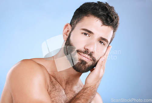 Image of Skincare, cosmetic and portrait of a man feeling face isolated on a blue background. Beauty, clean and model touching facial beard, grooming and cleaning for dermatology treatment on studio backdrop