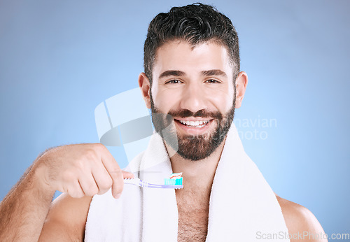 Image of Toothbrush, portrait and man cleaning in studio for dental wellness, healthy smile and mouth. Happy male model brushing teeth, face and care of fresh breath, oral gums or dentistry on blue background