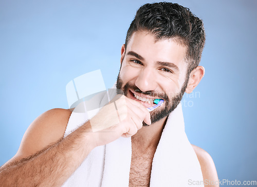 Image of Toothbrush, portrait and man brushing teeth in studio for dental wellness, healthy smile and mouth. Happy male model, oral care and fresh breath for gums, dentistry and hygiene on blue background