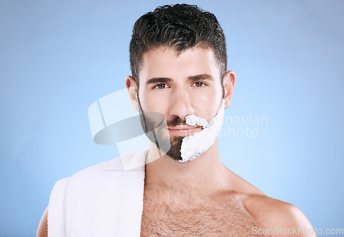 Image of Portrait of man with foam on half beard, with towel and skin product placement in studio mock up. Shaving cream on face, hair and skincare for happy male model grooming, isolated on blue background.