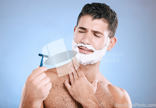 Image of Shaving, beard and confused man with razor in hand, foam product placement in studio mock up. Shave accident, cream on face and hair or skincare for male model grooming, isolated on blue background.