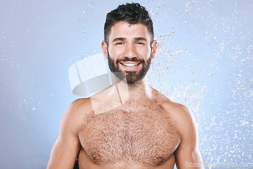 Image of Water splash, portrait and man in studio skincare, wellness and cleaning on blue background. Face, shower and happy male model relax in luxury, gentle and moisture for beauty, cosmetics or treatment