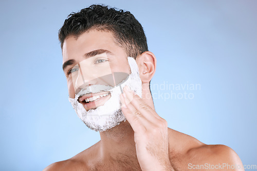 Image of Shaving, foam on beard and man with smile and hand on face, product placement and mock up in studio. Shave cream, hair and skincare for happy male model facial grooming, isolated on blue background.