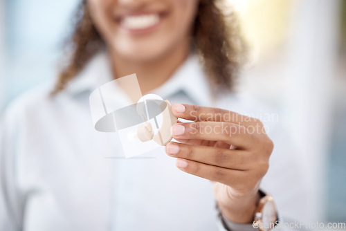 Image of Hand, hearing aid and disability with a black woman holding a listening device for dead people in a clinic. Medical, technology or insurance with a female medicine professional standing in a hospital