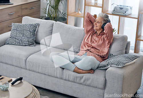 Image of Happy, smile and headphones with old woman on sofa for music, wellness and streaming. Mobile radio, podcast and technology with lady listening in living room at home for health, relax and zen mindset