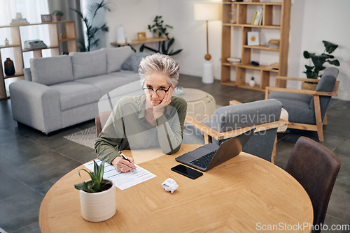 Image of Focus, portrait and senior woman writing ideas for work from home budget, financial planning and laptop. Thinking, serious and boss, executive or entrepreneur with paperwork fail, taxes and finance