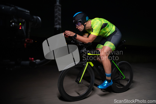 Image of A videographer recording a triathlete riding his bike preparing for an upcoming marathon.Athlete's physical endurance and the dedication required to succeed in the sport.