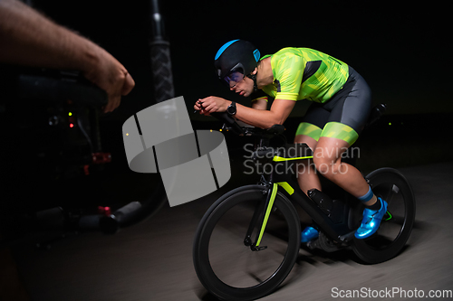 Image of A videographer recording a triathlete riding his bike preparing for an upcoming marathon.Athlete's physical endurance and the dedication required to succeed in the sport.