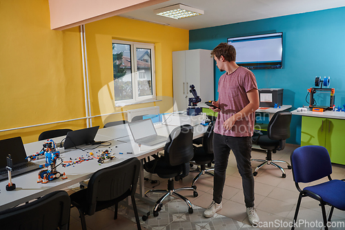 Image of A student testing his new invention of a robotic arm in the laboratory, showcasing the culmination of his research and technological prowess.