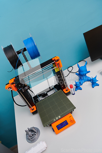 Image of Modern 3d printer for creating 3d models and materials on the table in the laboratories next to the computer