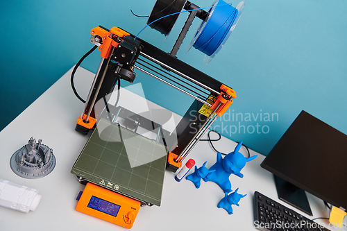 Image of Modern 3d printer for creating 3d models and materials on the table in the laboratories next to the computer