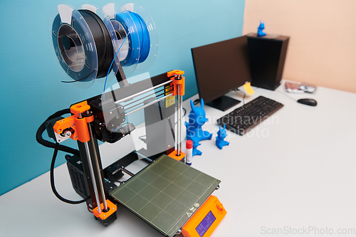 Image of Modern 3d printer for creating 3d models and materials on the table in the laboratories next to the computer