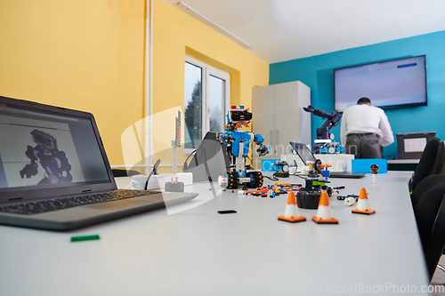 Image of A student testing his new invention of a robotic arm in the laboratory, showcasing the culmination of his research and technological prowess.