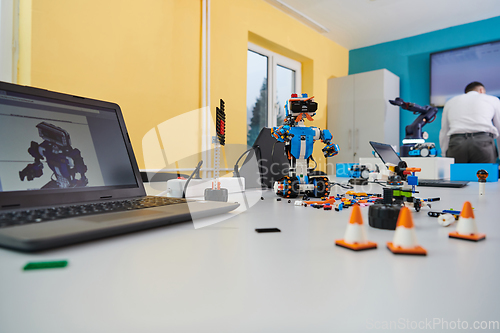 Image of A student testing his new invention of a robotic arm in the laboratory, showcasing the culmination of his research and technological prowess.