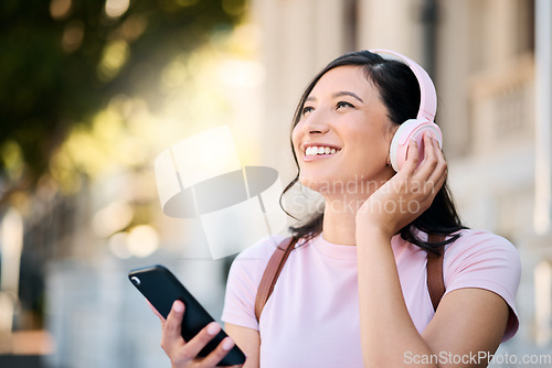 Image of Headphones, happy and music by woman in city for travel, mindset and smile on building background. Radio, podcast and travelling girl student with app, online audio or subscription service outside