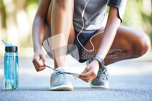 Image of Water, bottle and athlete tie laces ready to exercise, workout or fitness outdoors in a park by female training. Active, fit and closeup of person or runner preparing to jog for health and wellness