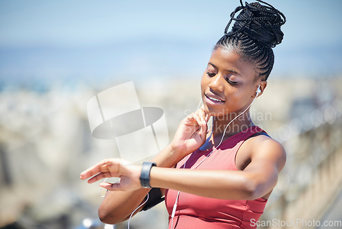 Image of Heart rate, smartwatch and runner time of a black woman by the sea doing exercise and running. Outdoor, run tracker app and mobile of a athlete with headphones by the ocean listening to audio