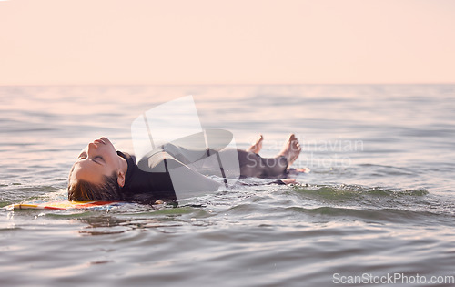 Image of Surfing, woman and lying on board in waves, sea and ocean for summer adventure, freedom and sky background. Calm female surfer relax in water, beach and swimming for tropical holiday, travel or peace