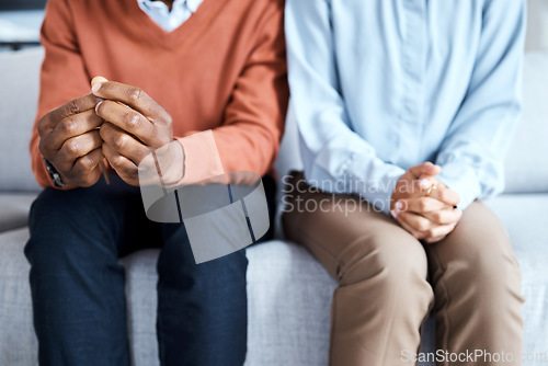 Image of Nervous, hands and couple in waiting room for results, cancer and bad news, diagnosis and stress. Hand, anxiety and man with woman on sofa for depression, marriage counseling or divorce discussion