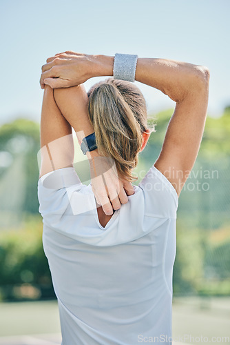 Image of Tennis, back and stretching arm with a sports woman on a court for a warm up before a competitive game. Sport, fitness or training with a female athlete getting ready for a practice match from behind