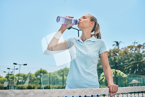 Image of Woman, tennis and drinking water for hydration after workout, exercise or intense training on court. Sporty female with bottle for refreshing drink, thirst or stay hydrated during sports exercising