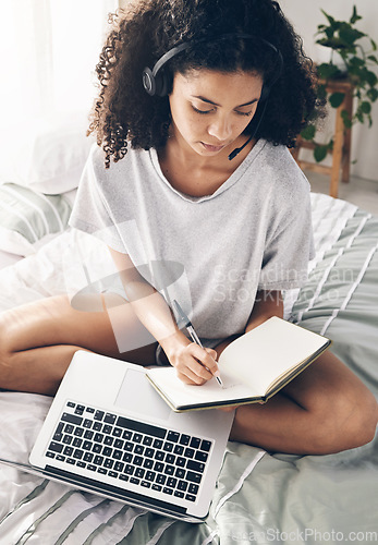Image of Book, writing and black woman with laptop and headphones for studying or online learning. Scholarship, student and female with headset, computer and notebook in virtual class on bed in bedroom home.