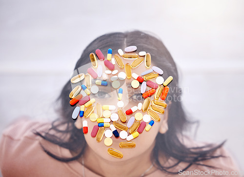 Image of Addiction, pills and medicine on woman face as drug abuse from overhead view looking serious and covered by medication. Tablets, issue and antibiotics problem by mental health patient or female