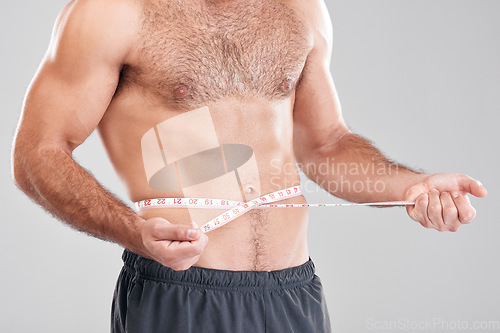 Image of Health, diet and man with measuring tape on stomach, healthy exercise weight loss and body care. Sports, nutrition and fitness, tracking weightloss and six pack progress isolated on grey background.