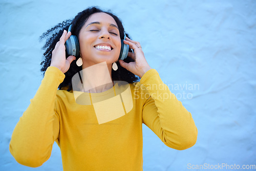 Image of Headphones, black woman and happy music on wall background, blue backdrop and mockup. Excited girl listening to radio, podcast and sound of streaming, audio and face of smile, relax and hearing tech