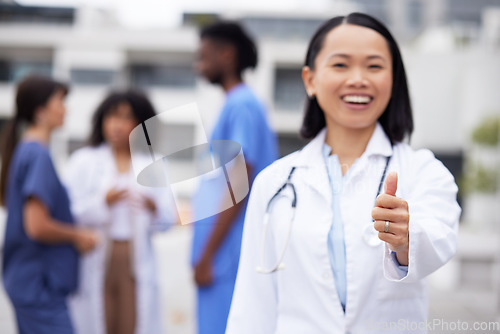 Image of Thumbs up, happy and portrait of a doctor outdoor of the hospital with a leadership mindset. Happy, smile and Asian female healthcare worker with a success or agreement gesture in a medical clinic.