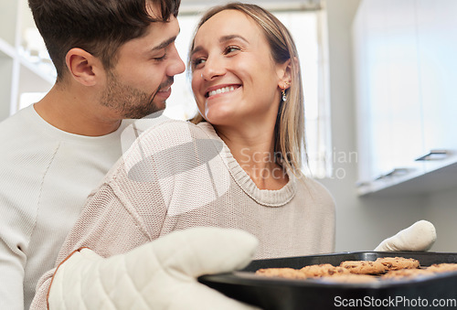 Image of Love, kitchen and couple baking cookies together for fun, bonding and romance in their home. Bake smile and happy young man and woman preparing biscuits or snacks for party, event or dessert at house