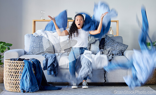 Image of Laundry, frustrated and upset woman in the living room throwing the clothes with anger at her home. Crazy, busy and angry female maid, housewife or cleaner with blur motion of dirty washing at house.