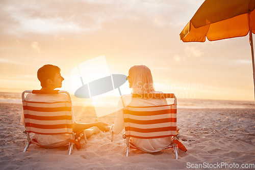 Image of Beach, back and couple holding hands during the sunset for support during a date on valentines day. Travel, relax and man and woman with affection, trust and conversation sitting by the ocean