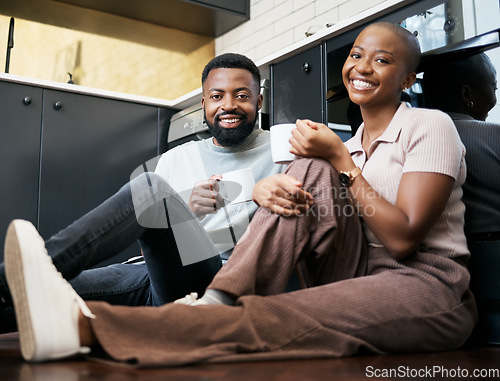 Image of Relax, smile and portrait of a couple with coffee on the kitchen floor in the morning. Love, happy and black man and woman drinking a cup of tea, latte or warm beverage with conversation together