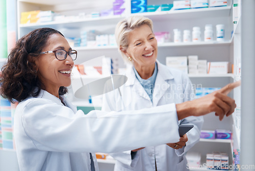 Image of Pharmacy women, shelf and pointing together with smile, stock and product for medical wellness in store. Pharmacist training, management and teamwork for medicine, service and healthcare in shop