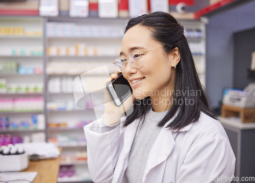 Image of Pharmacy, phone and healthcare worker talking with a mobile connection at work. Asian woman, pharmacist and business communication of a dispensary employee with a smile from conversation in store