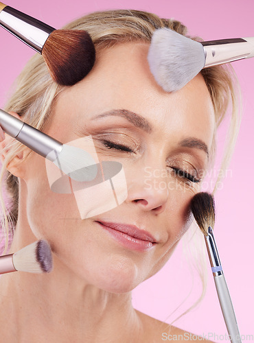 Image of Makeup, glam and face of a woman with brushes isolated on a pink background in a studio. Beauty, foundation and mature model with cosmetics from a beautician for a glamour look on a backdrop