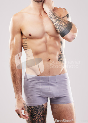 Image of Fitness, muscle and man body in studio with fitness, exercise and workout aesthetic. Isolated, gray background and studio with a sexy, strong and young male model in underwear with tattoos and abs