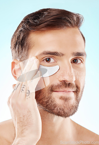 Image of Face, skincare and man with eye patch in studio isolated on a blue background. Beauty, portrait and male model with pad product for dermatology, cosmetics and facial treatment, wellness and health.