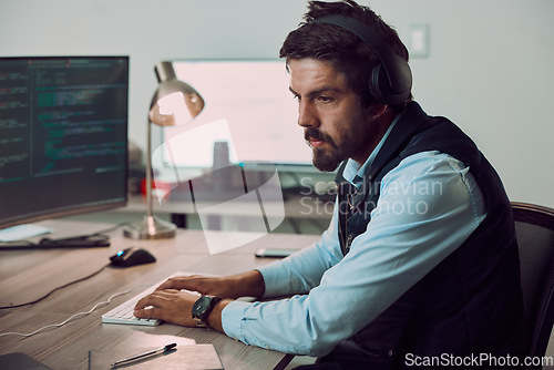 Image of Headphones, programmer and man typing on computer, coding or programming at night. Information technology, thinking and male developer or coder working on software while streaming music or podcast.