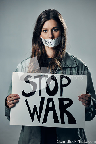 Image of War, stop and portrait of a woman with a sign while silent isolated on a grey studio background. Protest, crime and silenced girl with a board against conflict and violence in Russia on a backdrop