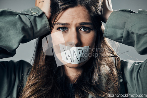 Image of Woman, face and protest with tape on mouth in fear for cold war, armageddon or doomsday against gray studio background. Female activist with voice message to stop or end global violence in society