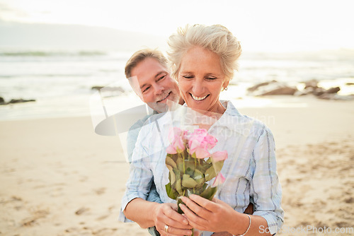 Image of Gift, celebration and senior couple with flowers at the beach for love, care and gratitude in Spain. Happy, vacation and elderly man with a bouquet surprise for a woman on valentines day at the ocean