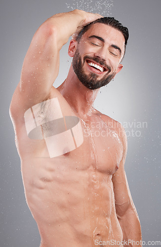 Image of Shower, clean and happy man in a studio for hygiene, grooming and body care for wellness. Water, washing and handsome male model doing a fresh morning health routine isolated by a gray background.