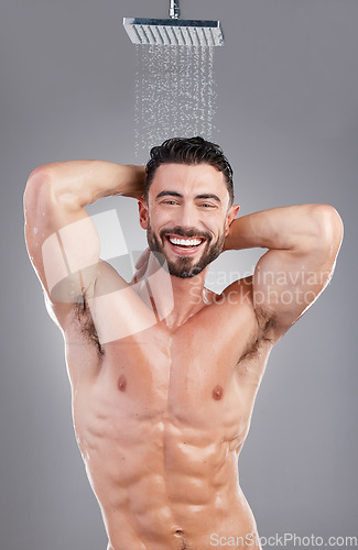 Image of Man, shower and cleaning in studio portrait by background, smile and hygiene to start morning. Model, abdomen and happy with water drops, wellness and healthy skincare process in bathroom for health