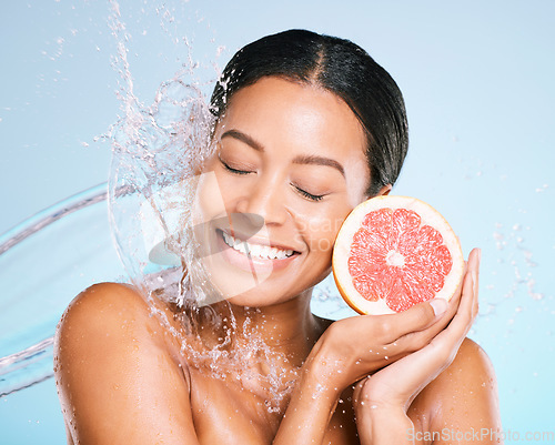 Image of Skin care, beauty and woman with a grapefruit for healthy skin and diet on a blue background. Face of aesthetic model person with water splash and fruit for sustainable facial health and wellness