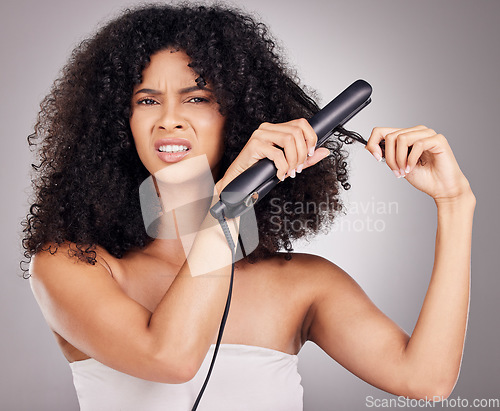 Image of Sad, face portrait and woman with hair straightener in studio isolated on gray background. Haircare damage, hairloss and black female model angry with flat iron for hairstyle after salon treatment.