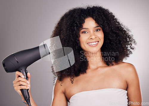 Image of Portrait, beauty and black woman with hair dryer in studio isolated on gray background. Haircare, aesthetic and female model with machine to dry hairstyle after salon treatment for growth or texture.